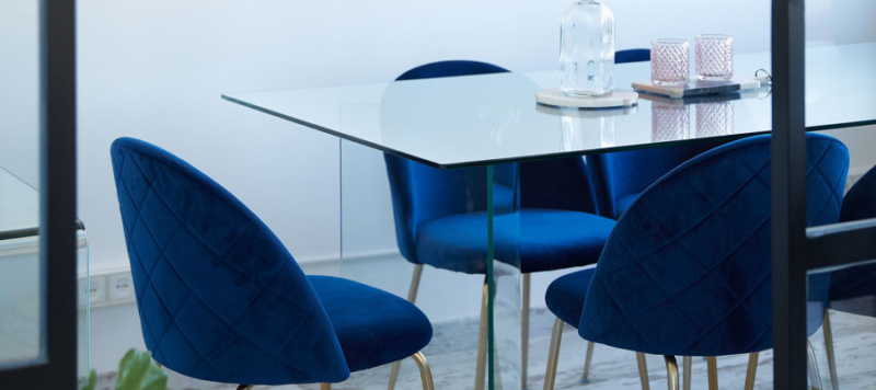 Glass dining table with 4 blue velvet chairs.