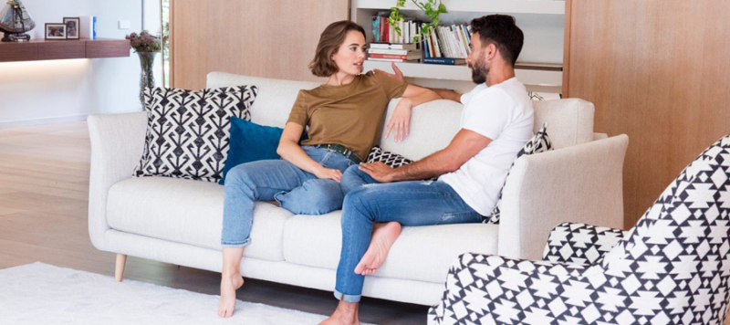 A couple talking on a fabric sofa.