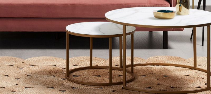 Round set tables in living room with white marble top and golden structured frames.