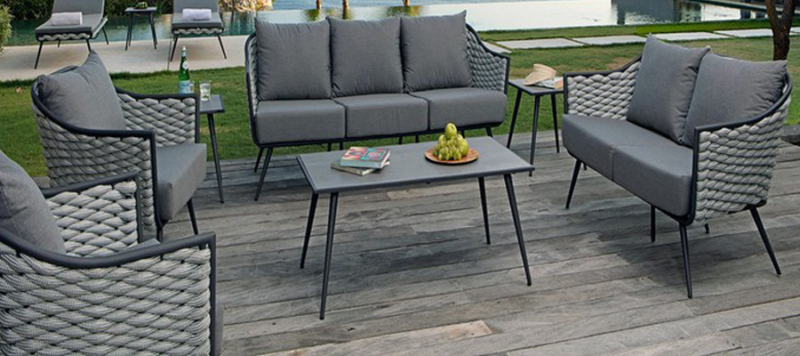 Rattan outdoor grey armchair with cushions, a coffee table and a sofa.
