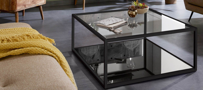 Square black glass coffee table near a sofa in a living room.