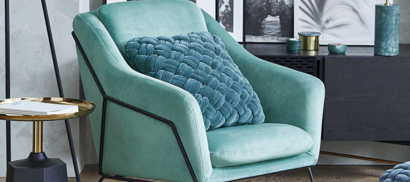 Green Brida armchair in living room near a side table and accessories.