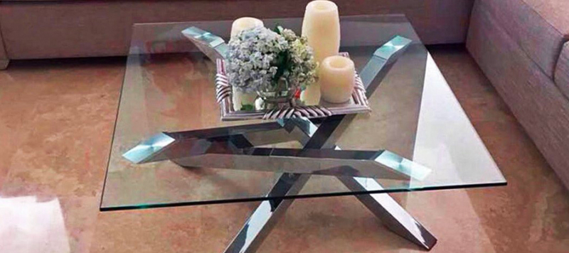 Elegant silver and glass top coffee table in a living room.
