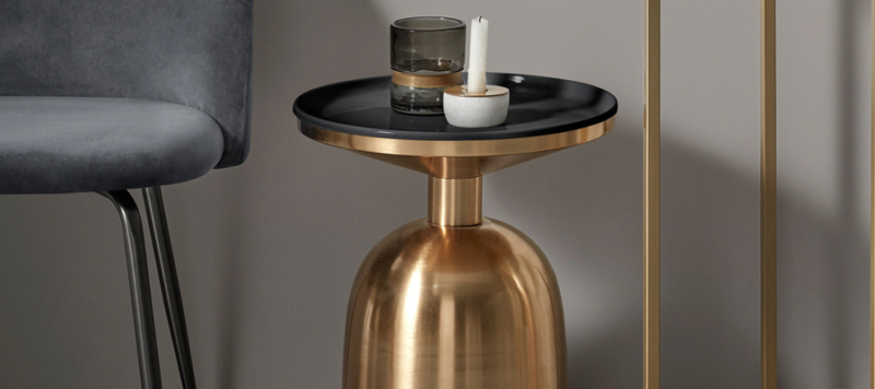 Living room side table in gold material and black top.